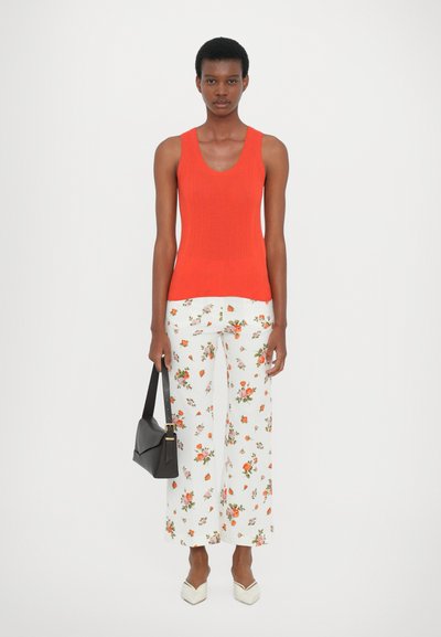 Red ribbed tank top, wide white floral-print pants, black shoulder bag, and white pointed-toe shoes. Clean lines and vibrant colors.