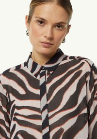 Sheer blouse featuring a tiger stripe pattern in shades of brown, cream, and orange. Classic collar and button-up front design.