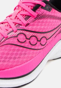 Φωτεινό ροζ αθλητικό παπούτσι με ύφασμα από δίχτυ, μαύρο κυκλικό λογότυπο, ροζ κορδόνια και λευκή σόλα με μαύρη επένδυση.