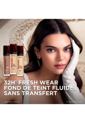 Trio de fond de teint de L'Oréal présenté : trois flacons transparents avec des pompes rouges. Un modèle portant un gant blanc affiche un look subtil et naturel avec une texture douce.