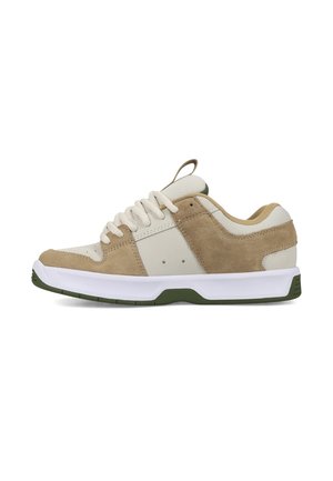 Beige-weißer Sneaker mit niedrigem Schnitt, Veloursleder-Details, weißen Schnürsenkeln und grünen Akzenten an Sohle und Fersenlasche, von der Außenseite gezeigt.