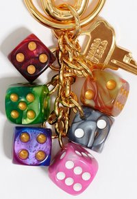 Portachiavi con sei dadi colorati: rosso, verde, viola, rosa, grigio e arancione, con punti dorati e bianchi, attaccati con una catena e una chiave dorata.