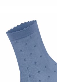 Chaussettes bleu clair avec un motif texturé et un design à pois. Le bord supérieur est festonné, ajoutant un détail ludique à la forme générale.