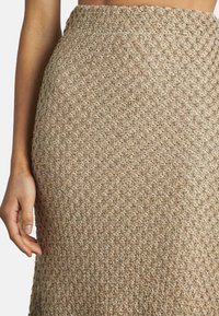 Gonna aderente fino al ginocchio in tessuto beige testurizzato con un motivo a diamante, caratterizzata da sottili fili multicolori e una vita elastica.