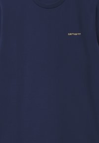 Camiseta de manga corta azul marino hecha de algodón, con un pequeño logo dorado en el pecho. Cuello redondo clásico con una textura suave.