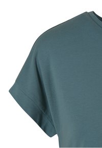 Kort mouw turquoiseblauw katoenen overhemd met geribbelde manchetten en een eenvoudige ronde halslijn op een witte achtergrond.