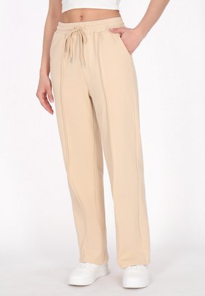 Beige sweatpants med elastisk talje og snøre, med sidelommer og en tapered design. Blødt stof med synlige syninger.
