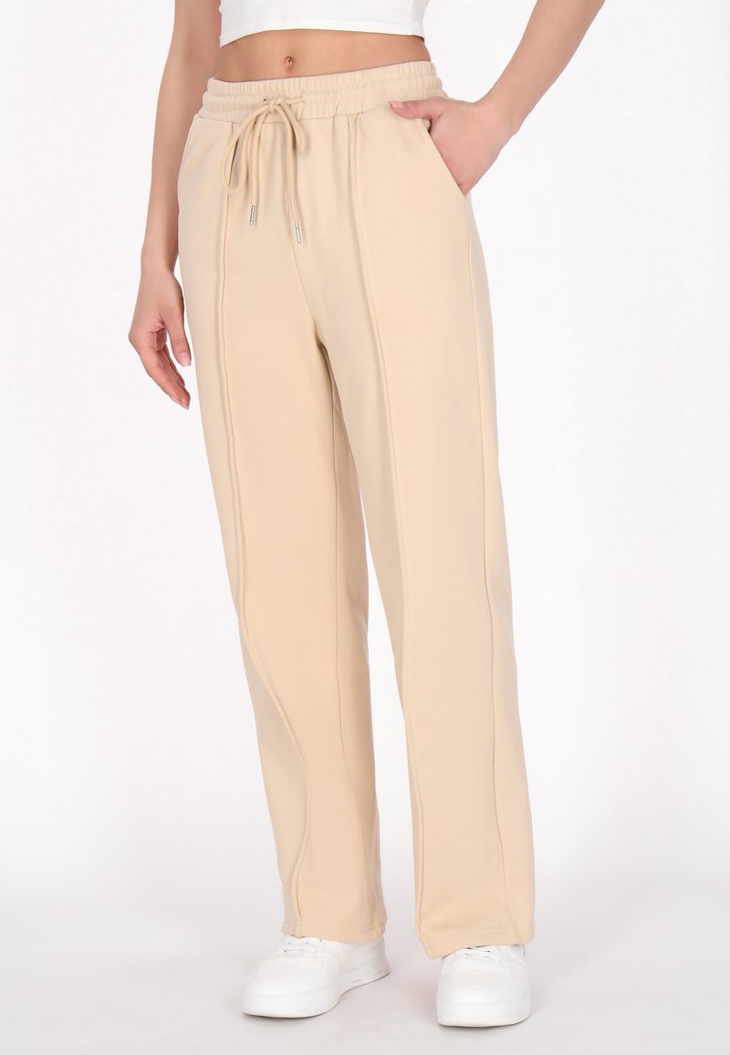 Beige sweatpants med elastisk talje og snøre, med sidelommer og en tapered design. Blødt stof med synlige syninger.