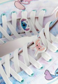 Sneaker in tela leggera con un motivo tie-dye pastello e dettagli di personaggi dei cartoni animati, complete di lacci bianchi. Dettagli blu e rosa in tutto il design.