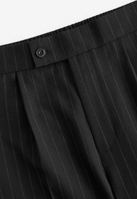 Pantaloni neri a righe con un tessuto texturizzato, dotati di chiusura con bottone in vita e pieghe per un tocco di dettaglio e stile.