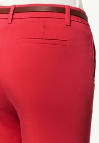 Rote Hosen mit einer glatten, flachen Stofftextur, dazu ein brauner Kunstledergürtel. Enthält eine einzelne Gesäßtasche mit einem dezenten Design.
