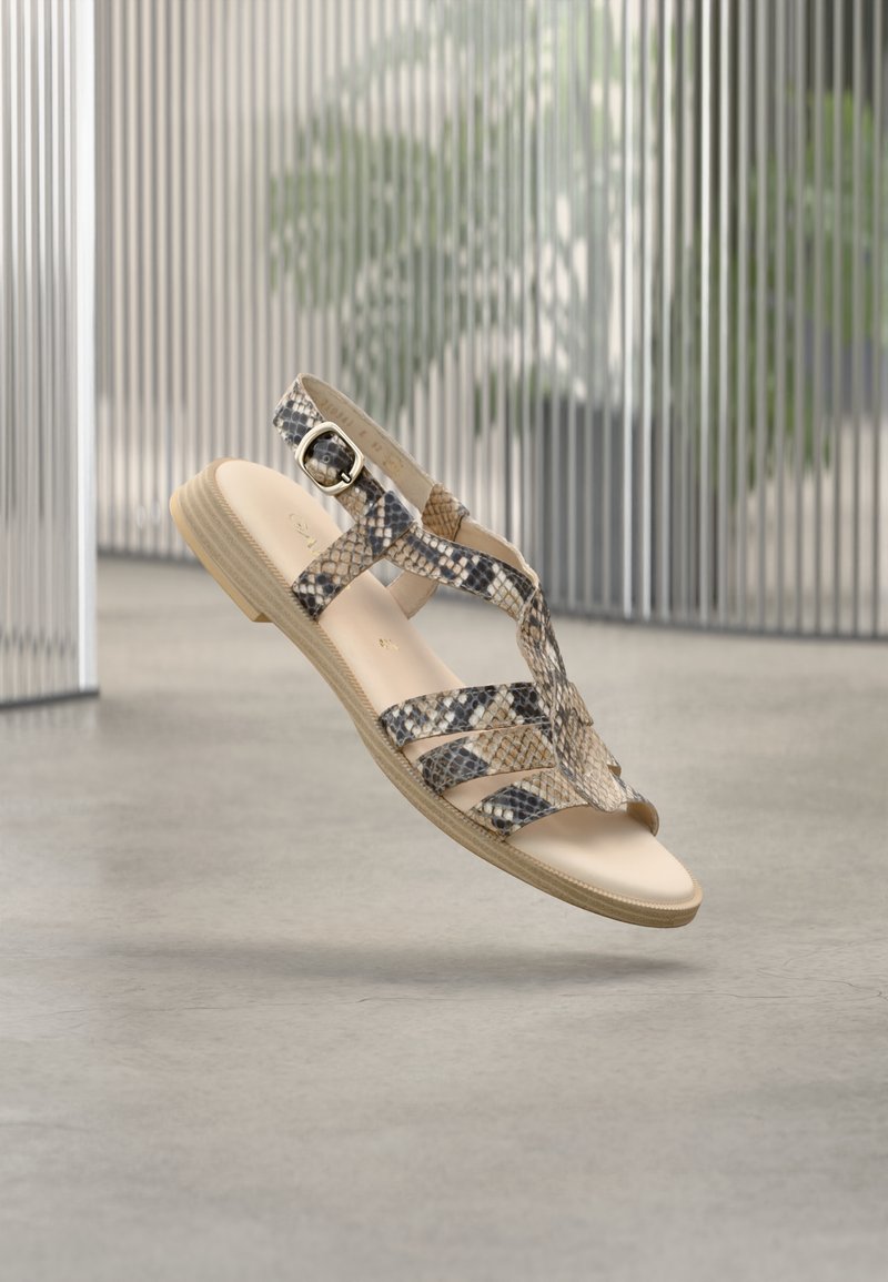 Σανδάλια με λουράκια σε μπεζ και σχέδιο φιδιού. Επίπεδη σόλα με υφή και ρυθμιζόμενο κουμπί. Ελαφρύ σχέδιο.