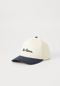 Baseball cap made of cotton; cream upper with navy blue brim. Features embroidered text "les deux" on the front. Round shape with a button on top.