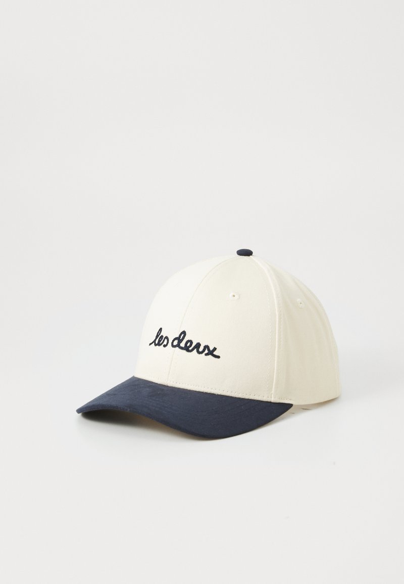 Baseball cap made of cotton; cream upper with navy blue brim. Features embroidered text "les deux" on the front. Round shape with a button on top.