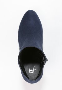 Námořnické modré kotníkové boty vyrobené z měkkého semiše s špičatou špičkou a bočním zipem pro zapínání. Vnitřní podšívka je černá s logem.