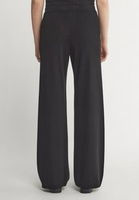 Svarta vida byxor i mjukt, stretchigt tyg. Slät yta, elastisk midja och uppvikta fållar. Minimalistisk design.