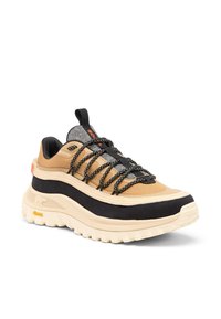 Ruskeat ja mustat urheilukengät, joissa paksu kerma valkoinen pohja, harmaat yksityiskohdat, mustat nauhat ja vetokahva. Kuviollinen päällinen koristeltu ompelukuvioilla.