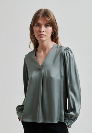 Blusa a maniche lunghe in satin verde spento con scollo a V e maniche arricciate, caratterizzata da una vestibilità rilassata e un sottile dettaglio di plissé nella parte frontale.