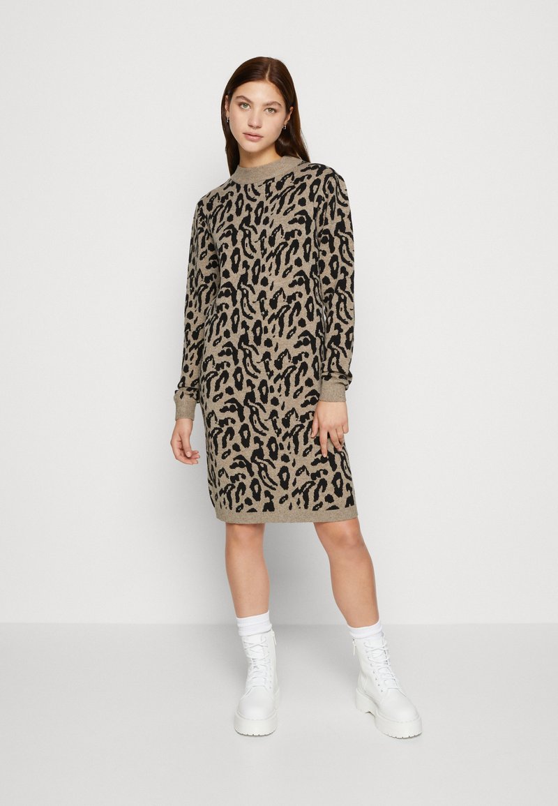Beige en zwarte dierenprint jurk met een ronde halslijn en lange mouwen, gecombineerd met witte chunky laarzen.