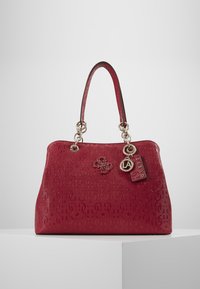 Sac à main rouge gaufré avec une surface texturée, doté de ferrures argentées, de deux anses et de breloques logo. Forme rectangulaire, taille moyenne.