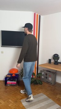 Orange mushroom-shaped lamp on a blue table, wood floor with a striped wall. Casual clothing, light fabric, blue jeans, and white sneakers.