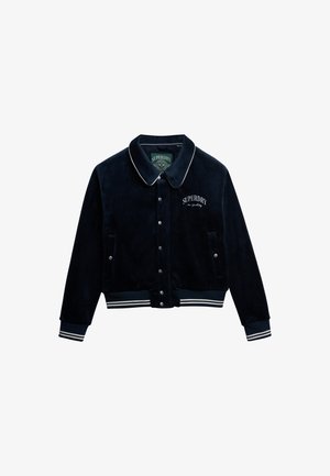 Chaqueta de terciopelo azul marino con ribete blanco y logotipo bordado "Superdry". Presenta botones a presión, puños acanalados y una banda en la cintura.