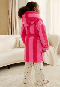 Fleece bathrobe in pink shades with striped design, featuring a hood, belted waist, and front pockets, paired with white pants adorned with hearts.