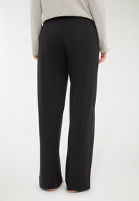 Pantaloni neri a gamba larga realizzati in tessuto liscio, dotati di una vita elastica e un taglio dritto, senza motivi o dettagli visibili.