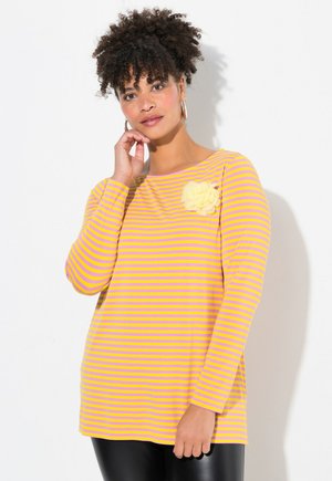 Blusa de manga larga a rayas en amarillo y lavanda, con escote redondo y una flor de tela en el hombro izquierdo. Textura suave, corte holgado.