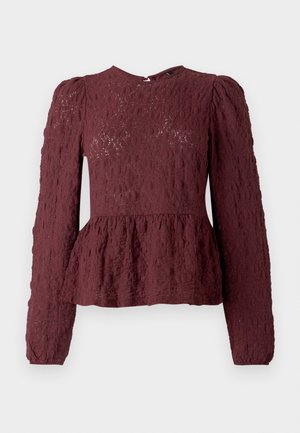 Burgundski peplum top iz teksturirane čipke, z dolgimi rokavi, visokim ovratnikom in diskretno plisirano pasico. Zadrga na hrbtni strani.