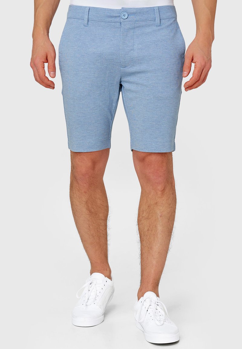 Lyseblå shorts lavet af blødt stof, med flad front, bæltestropper og knaplukning. Bruges med hvide sneakers.