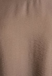 Tejido marrón texturizado con una apariencia suave y tejida, que presenta un brillo sutil y un color uniforme en toda su superficie.