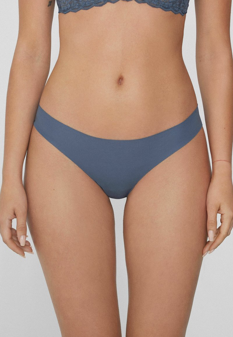 Culotte de bikini bleue, sans couture, fabriquée en matériau doux, dotée d'une taille basse et d'une texture lisse, offrant un ajustement confortable.