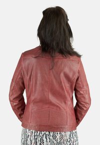Chaqueta de piel roja con hombros texturizados y acentos geométricos, con un diseño ajustado y acabado suave. Vista desde la parte posterior.