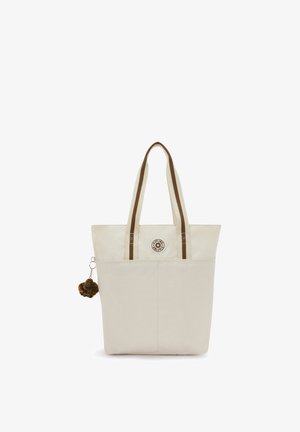 Beige tote bag with brown-striped handles, front pocket, round logo, and small brown furry monkey keychain attached on the left side.