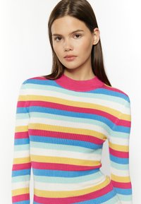 Maglione a coste con colletto alto rosa, caratterizzato da righe orizzontali in azzurro chiaro, giallo, bianco e rosa. Design aderente.