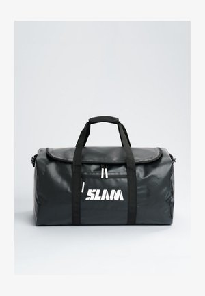Bolsa de deporte negra con dos asas, una correa para el hombro, un bolsillo delantero con cremallera y un logotipo blanco estilizado, sobre un fondo liso y claro.