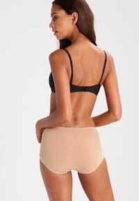 Svart BH og beige hipster undertøy. BH-en har justerbare stropper, mens undertøyet har en glatt, sømløs finish.