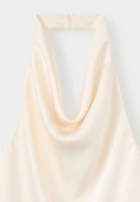 Top dos nu en satin crème avec un décolleté drapé et une fermeture par bouton dans le dos du cou.