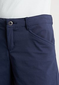 Bermudas de algodón azul marino con una textura suave, que cuentan con un bolsillo frontal, cierre de botón y detalles de costura sutiles.