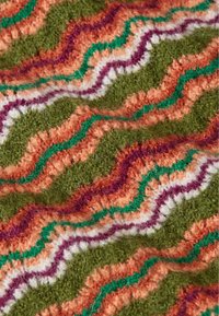 Texturerat tyg i ett orange, grönt och lila zigzag-mönster. Består av mjukt, luddigt material liknande ull med kontrasterande vita detaljer.