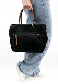 Sac à main en tissu noir avec des poignées en cuir marron, quincaillerie argentée, poche zippée à l'avant, forme rectangulaire et détail de marque subtil.