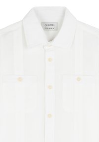 Chemise blanche à boutons avec col pointu, deux poches poitrine à rabats boutonnés, et étiquette indiquant la marque Scalpers et la taille 10/CN 140-55.