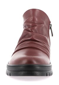 Stivaletto alla caviglia in pelle bordeaux con design stropicciato, suola bassa in gomma nera, chiusura laterale con zip e texture liscia.