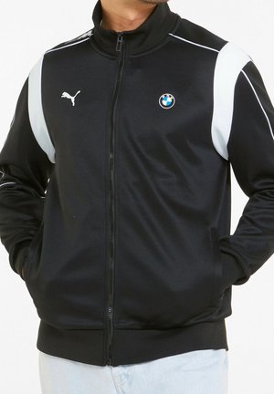 Zwarte zip-up jas met witte zijaccenten, voorzien van een Puma-logo en een BMW-badge op de borst. Gemaakt van glad, lichtgewicht materiaal.