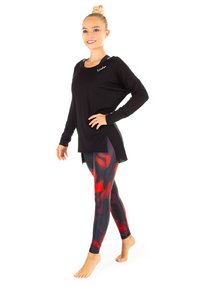 Musta pitkähihaisen paita, jossa on pyöreä helma, yhdistettynä tiukkoihin legginsseihin, joissa on punamustaa abstraktia kuvioa.