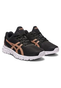 Zapatillas deportivas negras con una parte superior de malla transpirable, con acentos en oro rosa y suelas de goma blanca con un diseño texturizado.