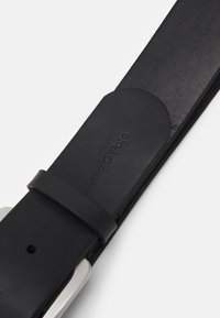 Schwarzer Ledergürtel mit glatter Textur, silberner Metallschnalle und geprägt logo. Einfaches Design mit sauberen Abschlüssen und sichtbaren Nähten.