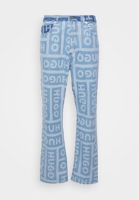 Jeans de mezclilla azul claro acampanados que presentan un patrón de logo repetido en azul más oscuro, diseño de cinco bolsillos y cierre de botón metálico.