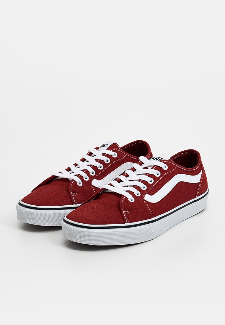 Zapatillas de lona rojas con cordones blancos, raya lateral, ribete negro y suelas de goma. El diseño incluye una puntera redondeada y un tacón plano.